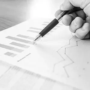 Ein Chart mit Grafiken zu einer Entwicklung ist zu sehen. Eine Hand mit Stift zeigt auf die Grafik.